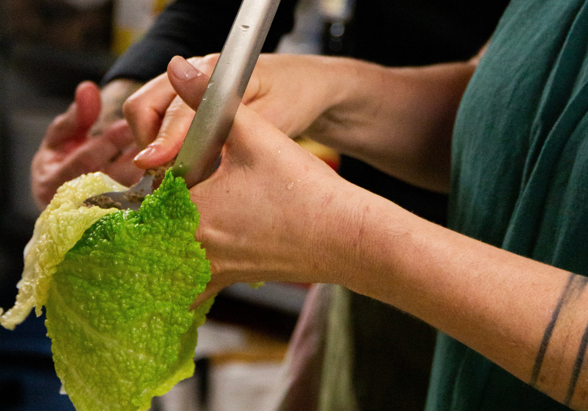 Un chef et deux participant·es cuisinant ensemble autour d'un plan de travail lors d'un atelier de cuisine végétale à Marseille — ALIMA